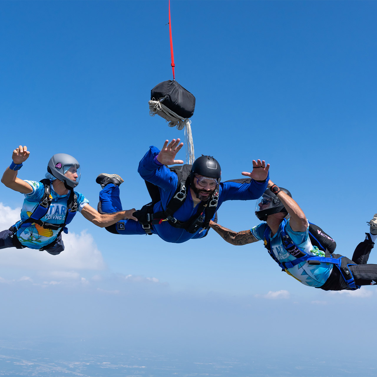 A learn to skydive AFF jumper and his two instructors in freefall moments after the student has deployed his pilot chute
