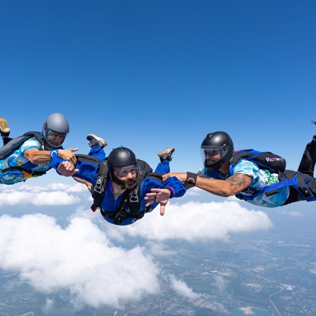 AFF student with two instructors with a small wisp of cloud in the background