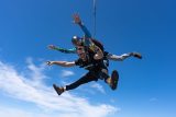 Male tandem skydiving pair smiling in the air.