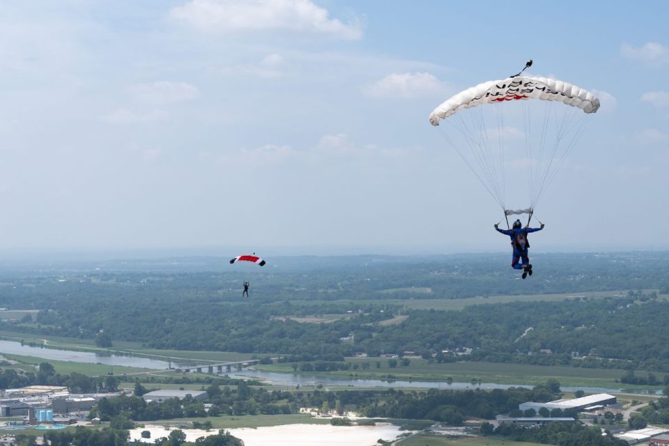 Two licensed skydivers under canopy.