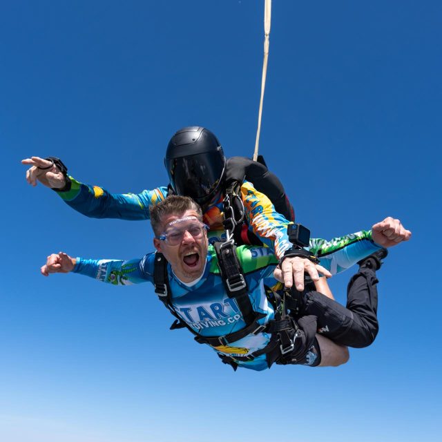 A tandem student yells with excitement while in freefall at Start Skydiving