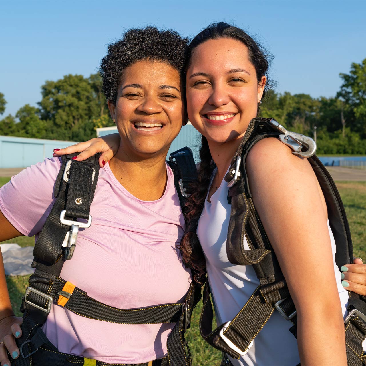 Female tandem skydivers hugging after landing.