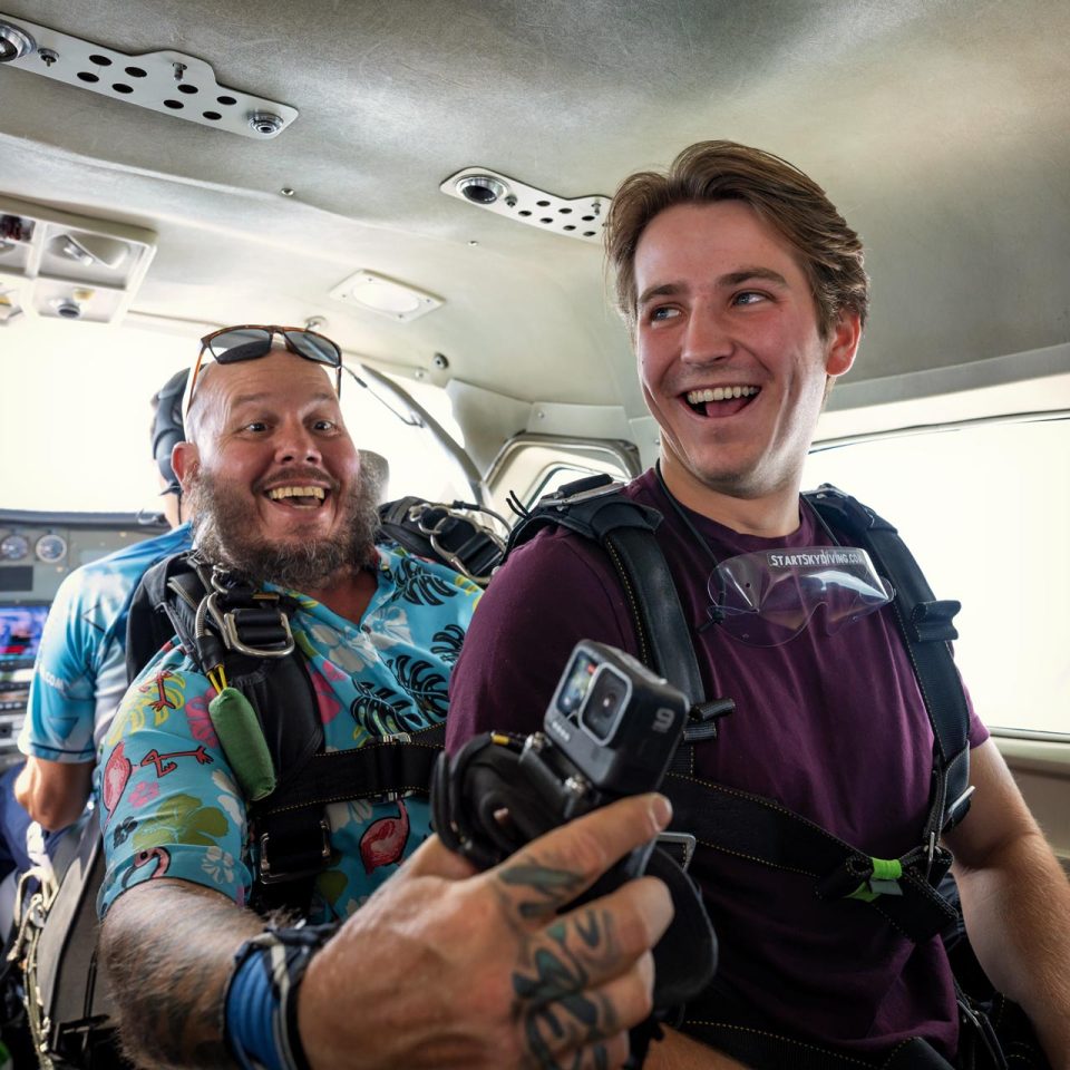 Male tandem instructor and his student smile on the plane at Start Skydiving.