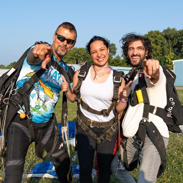 Brunette female tandem student posing with her tandem instructor and videographer after landing
